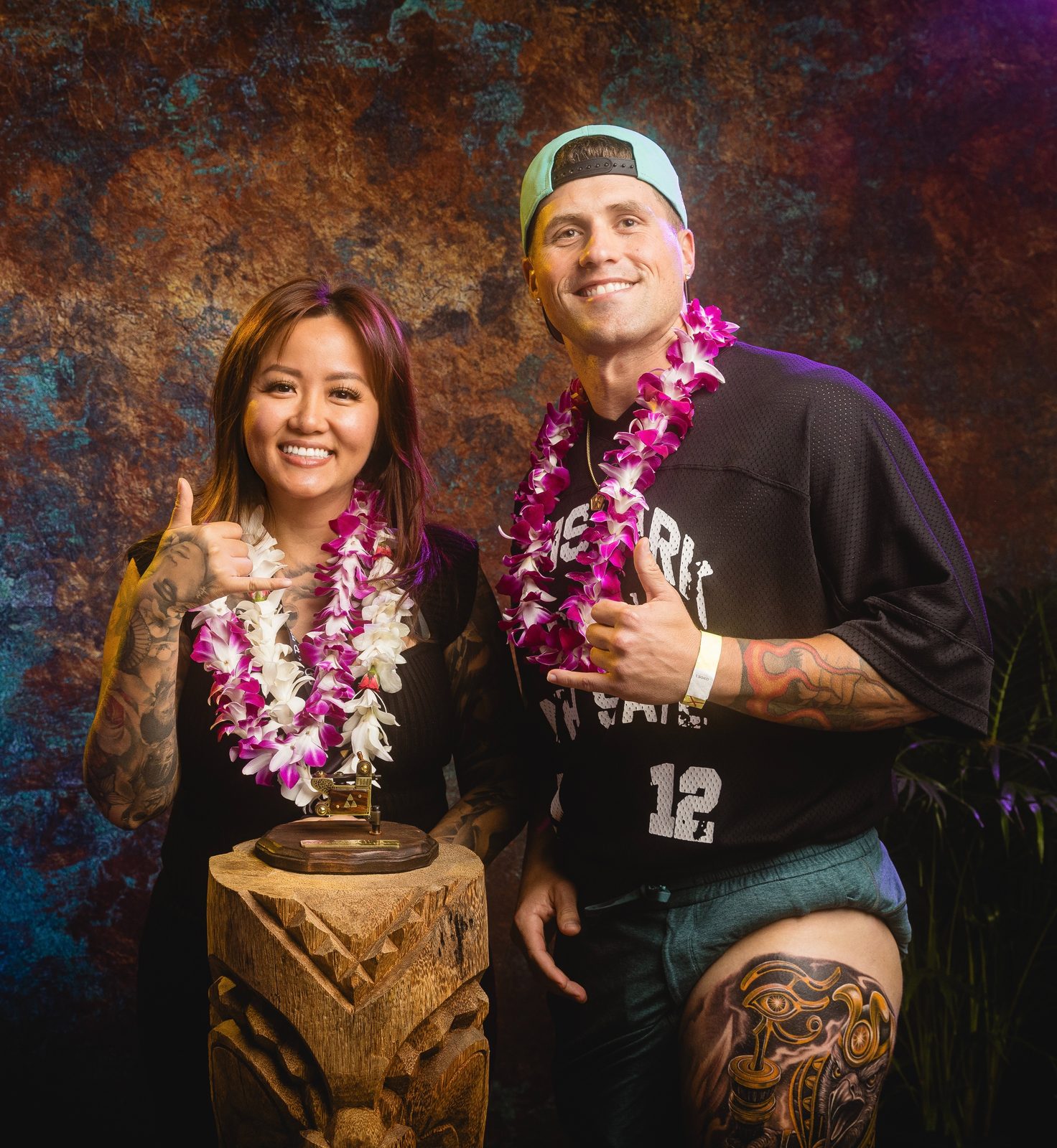 Lynn Hoang and a client with lei and a tattoo machine trophy