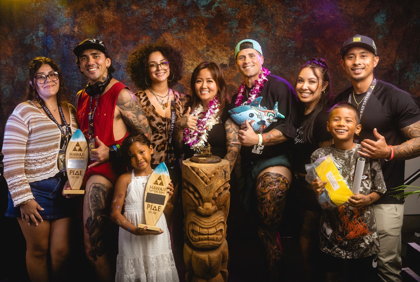 Lynn Hoang with clients and their families holding Hawaii Tattoo Expo trophies